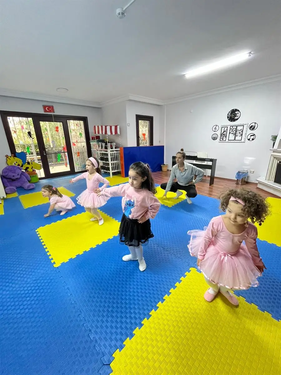 Bale kıyafetleriyle salonda hareket çalışan çocuklar ve eğitmenleri