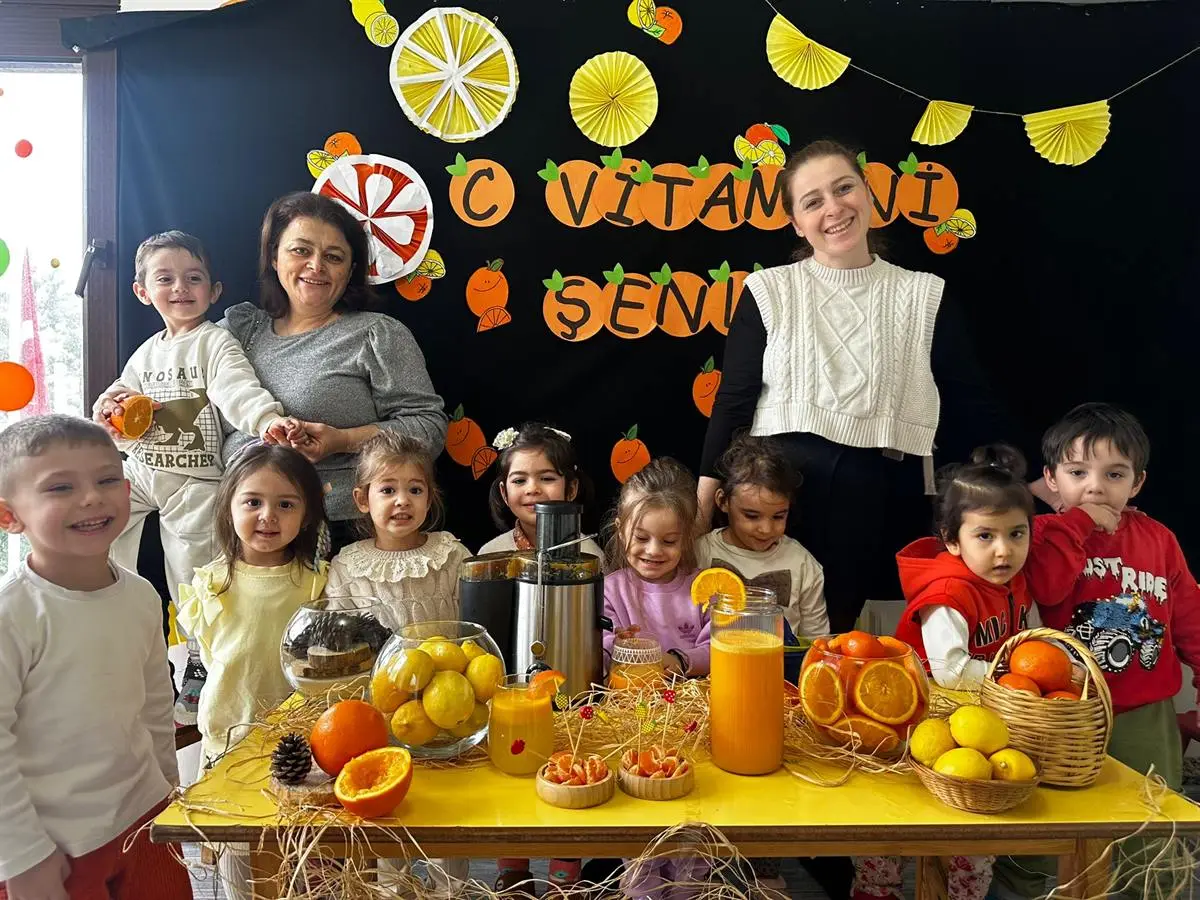 Portakal ve limon dolu şenlik masasının başında toplanan çocuklar ve öğretmenler